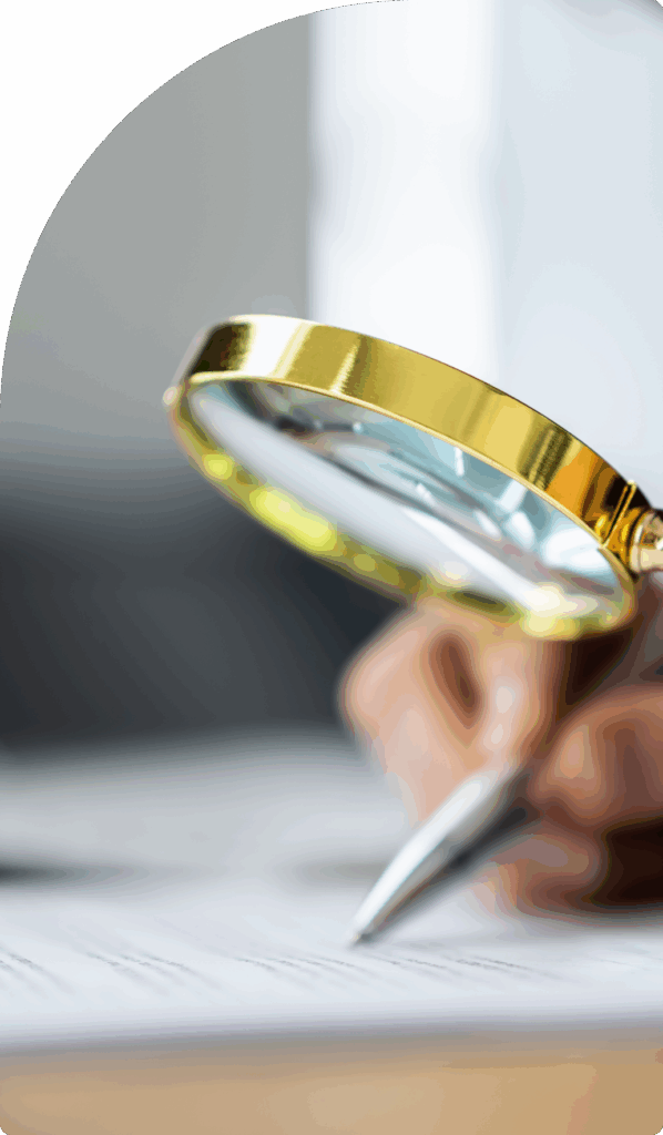 Close-up of a hand inspecting financial documents with a magnifying glass and pen, symbolising precise audit services in Dubai.