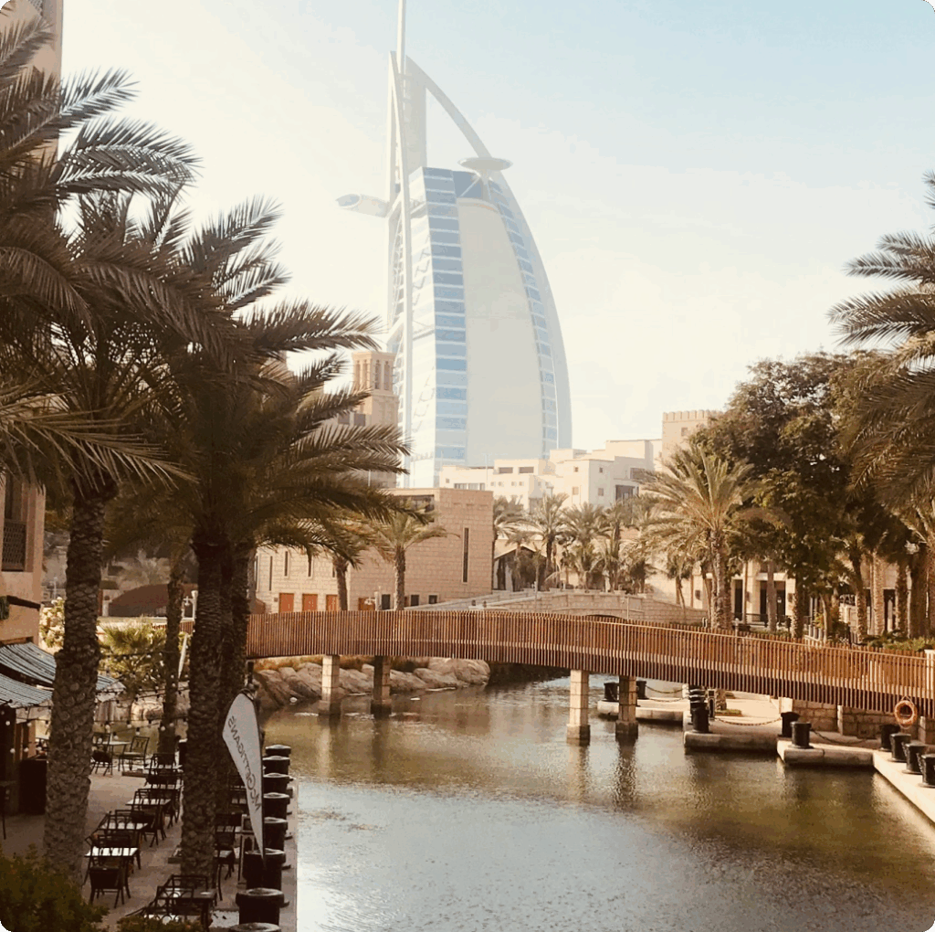 Scenic view of Burj Al Arab from a waterway with palm trees, reflecting the luxury and location benefits of DMCC company formation.