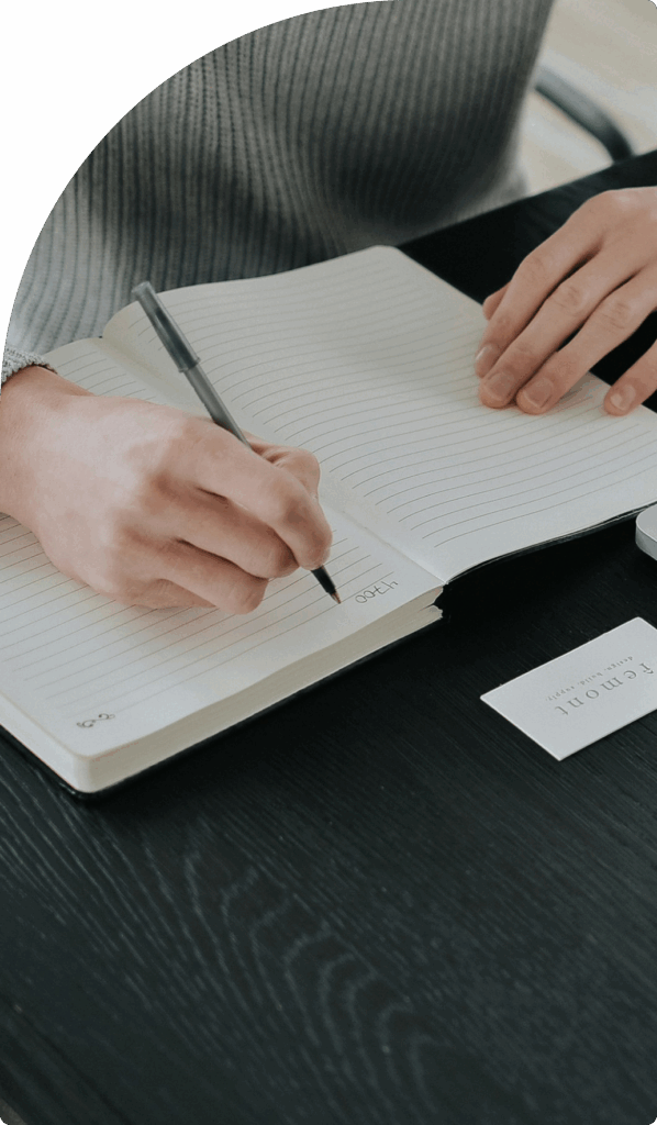 Close-up of hands writing in a lined notebook, representing strategic planning and idea development for DMCC company formation in Dubai.