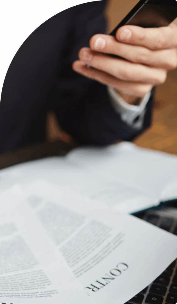 Close-up of a person reviewing contracts on a desk with a phone, symbolising relocation work.