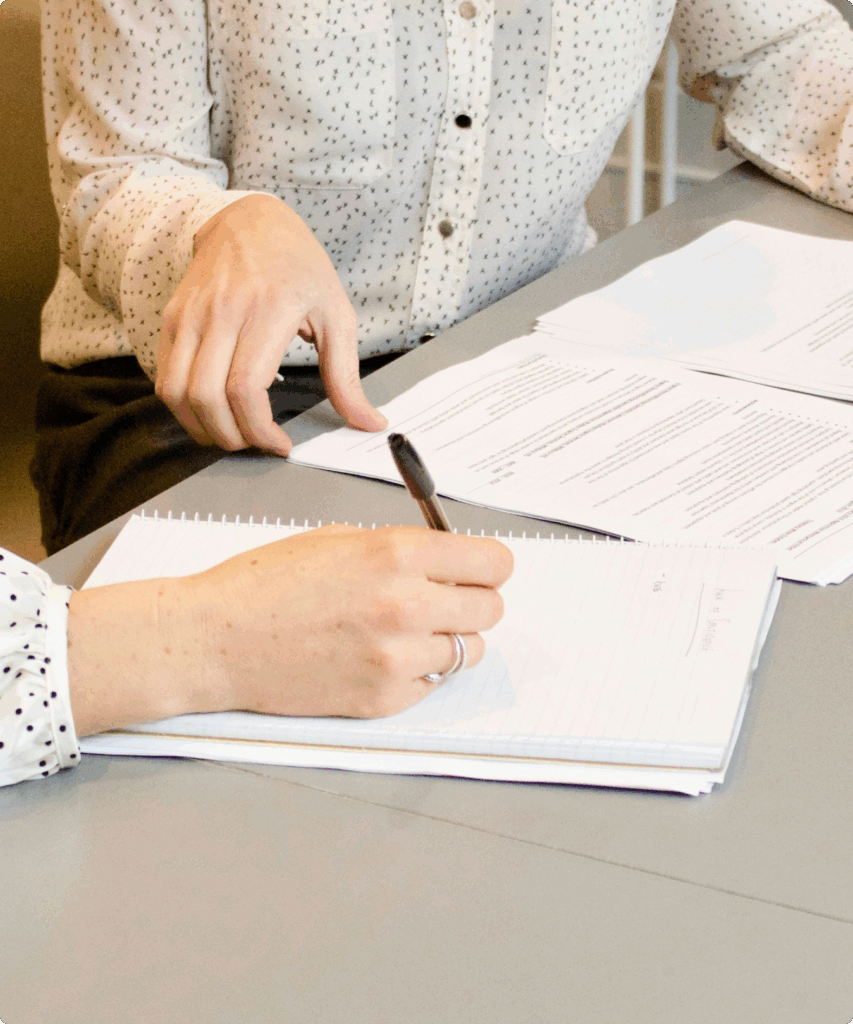 Two professionals reviewing documents and taking notes, discussing legal services in Dubai.