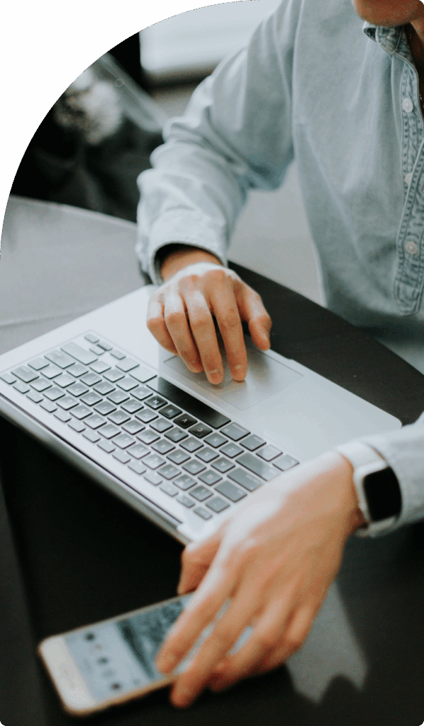 Close-up of person using laptop and smartphone, symbolising digital process and ease of mainland company formation in Dubai.