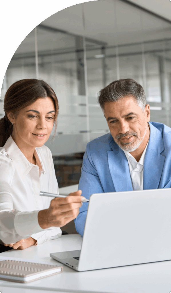 Two tax consultants in Dubai discussing financial strategy while reviewing data on a laptop.