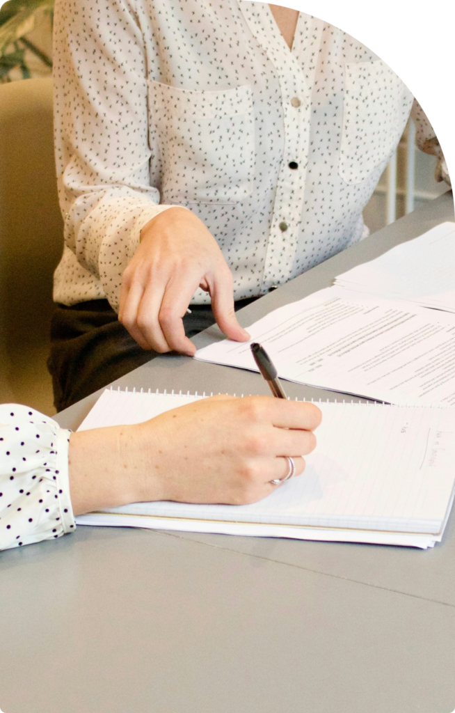 Two professionals in a business meeting reviewing and discussing documents, with one taking notes, symbolizing teamwork, negotiation, and strategic planning.