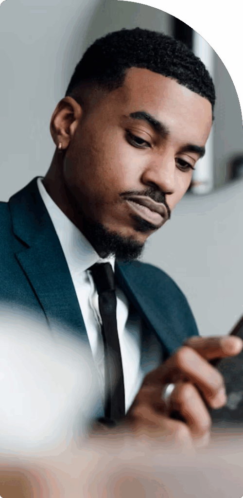 Focused young businessman in a suit using a smartphone, representing mobile access and efficiency in UAE free zone business setups.