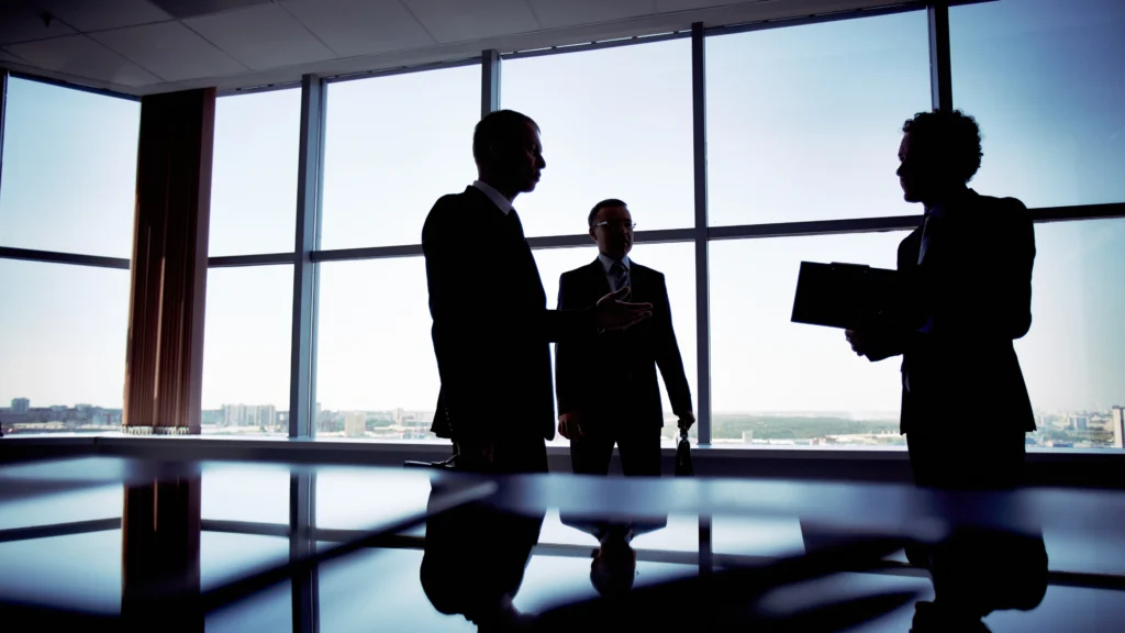 three men in their office standing and talking about business