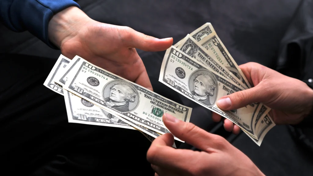 a person handing lots of money to another person