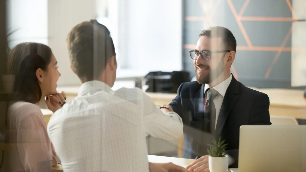 a man meeting with two clients in his office and discussing things