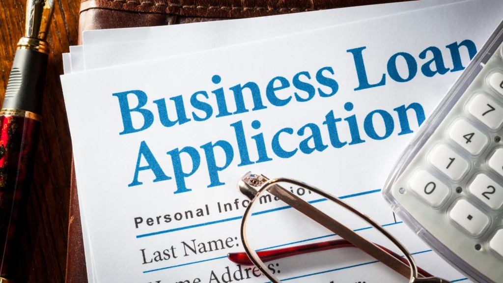 a pair of glasses and a cellphone on top of a bussiness loan applications