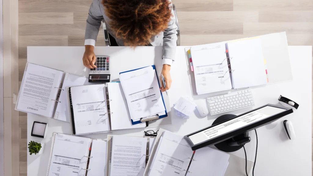 a person very carefully going through several important documents on a desk