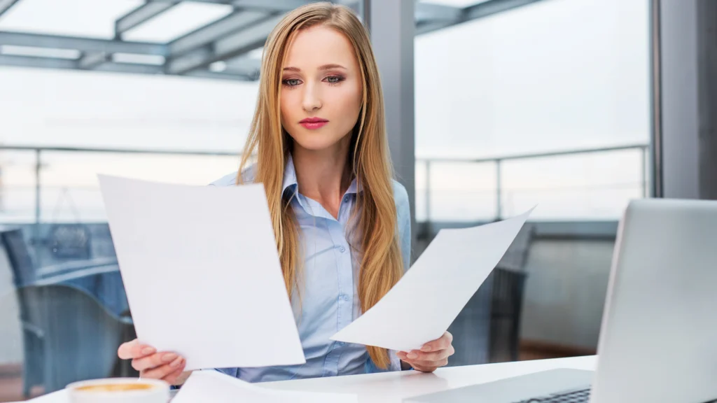 A woman at her workplace going over two different options on paper