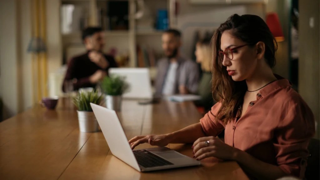 a woman sitting at home taking a remote work meeting on her laptop