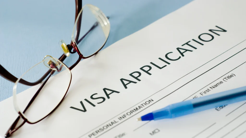 a visa application, a pen, and glasses in focus