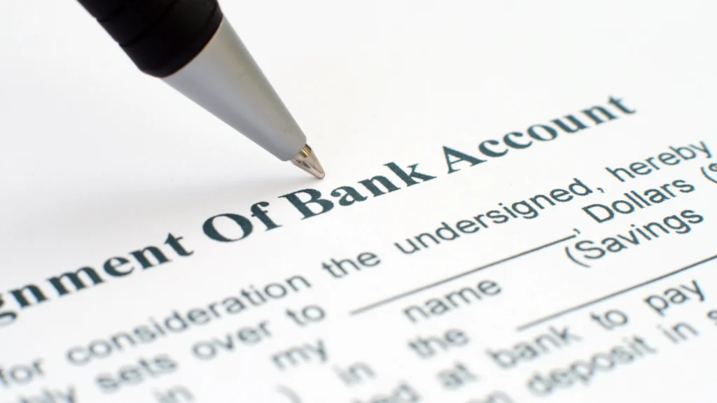 the word bank account in focus on a document with a pen held over it
