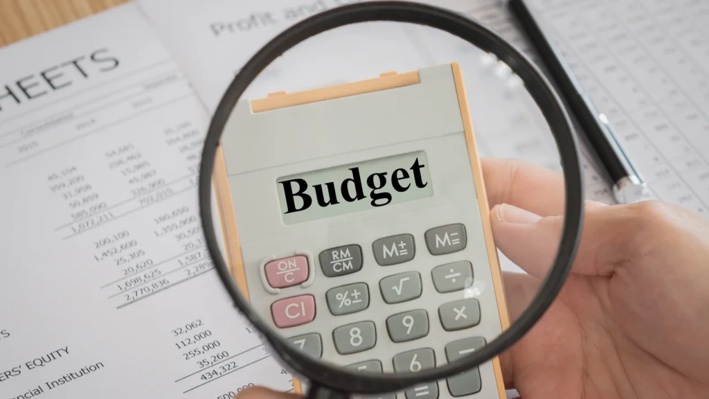 a magnifying glass focusing on a calculator that says budget