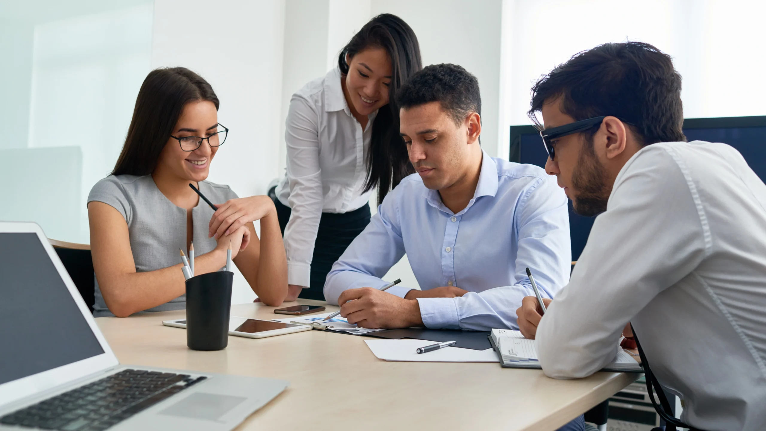 four office workers looking at a notebook with important information on it