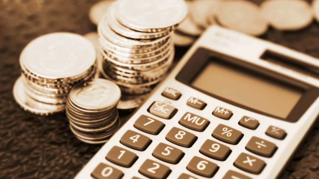 a calculator and stacks of coins on top of a table