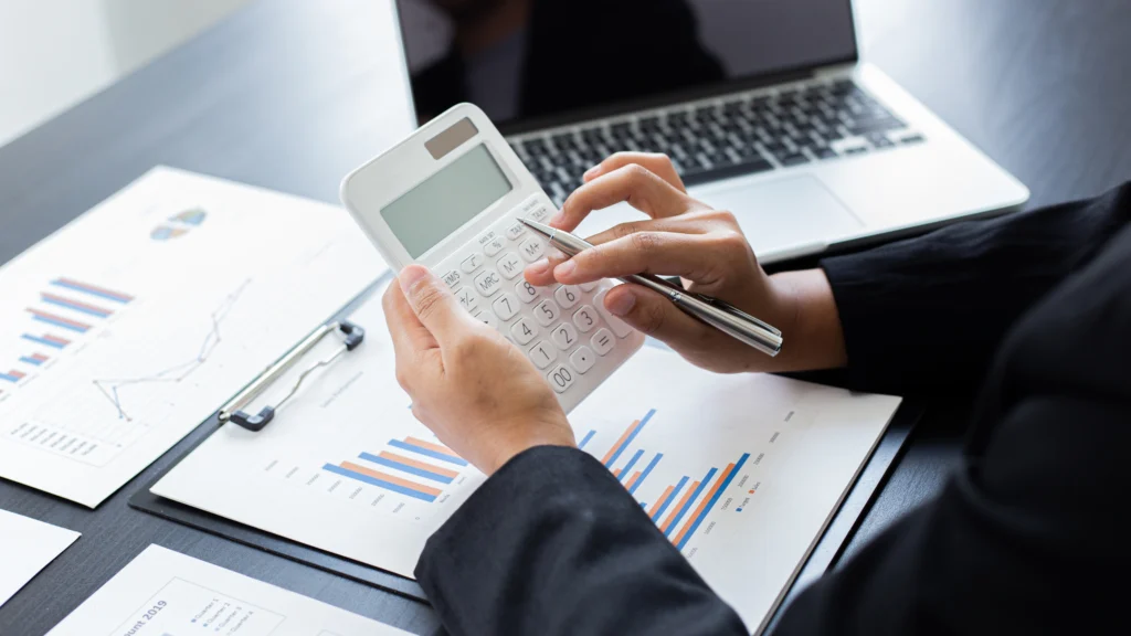 man using a calculator while going over important documents and graphs