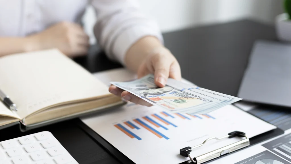 a man holding money on top of important documents
