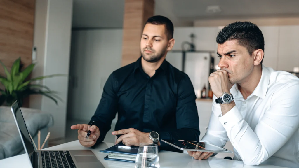 two men monitoring something on their laptop