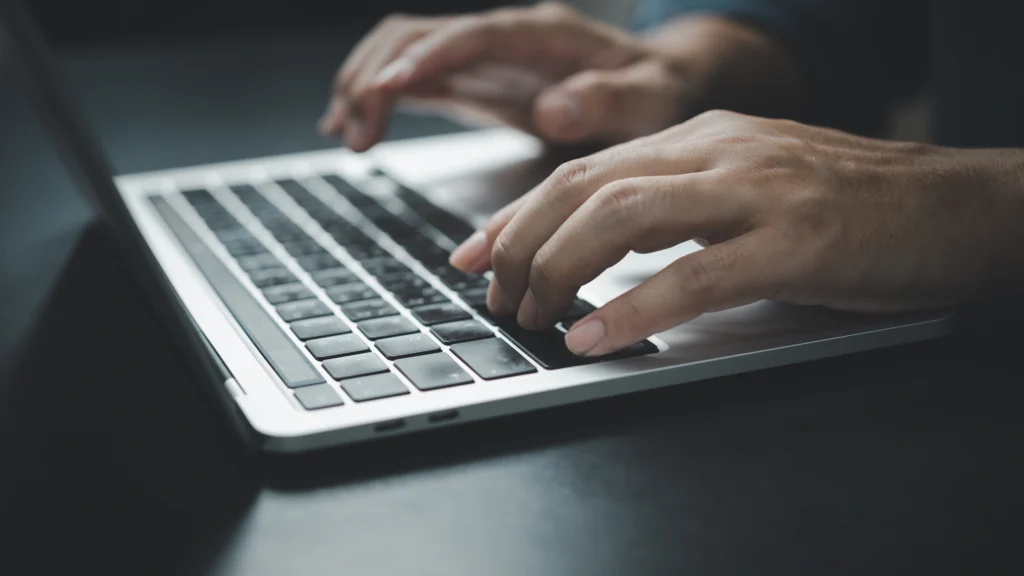 a man typing on a laptop keyboard to use social media