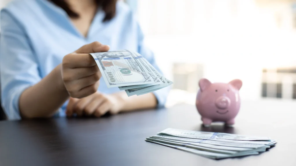 a person handing someone money, with a piggy bank on the table