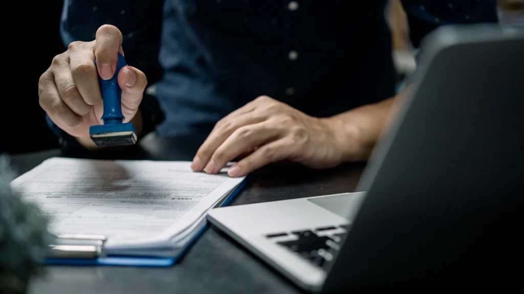 a businessman approving a transfer of shares with a laptop in front of him