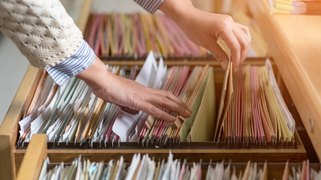 a person arranging a lot of documentation stacked in drawers