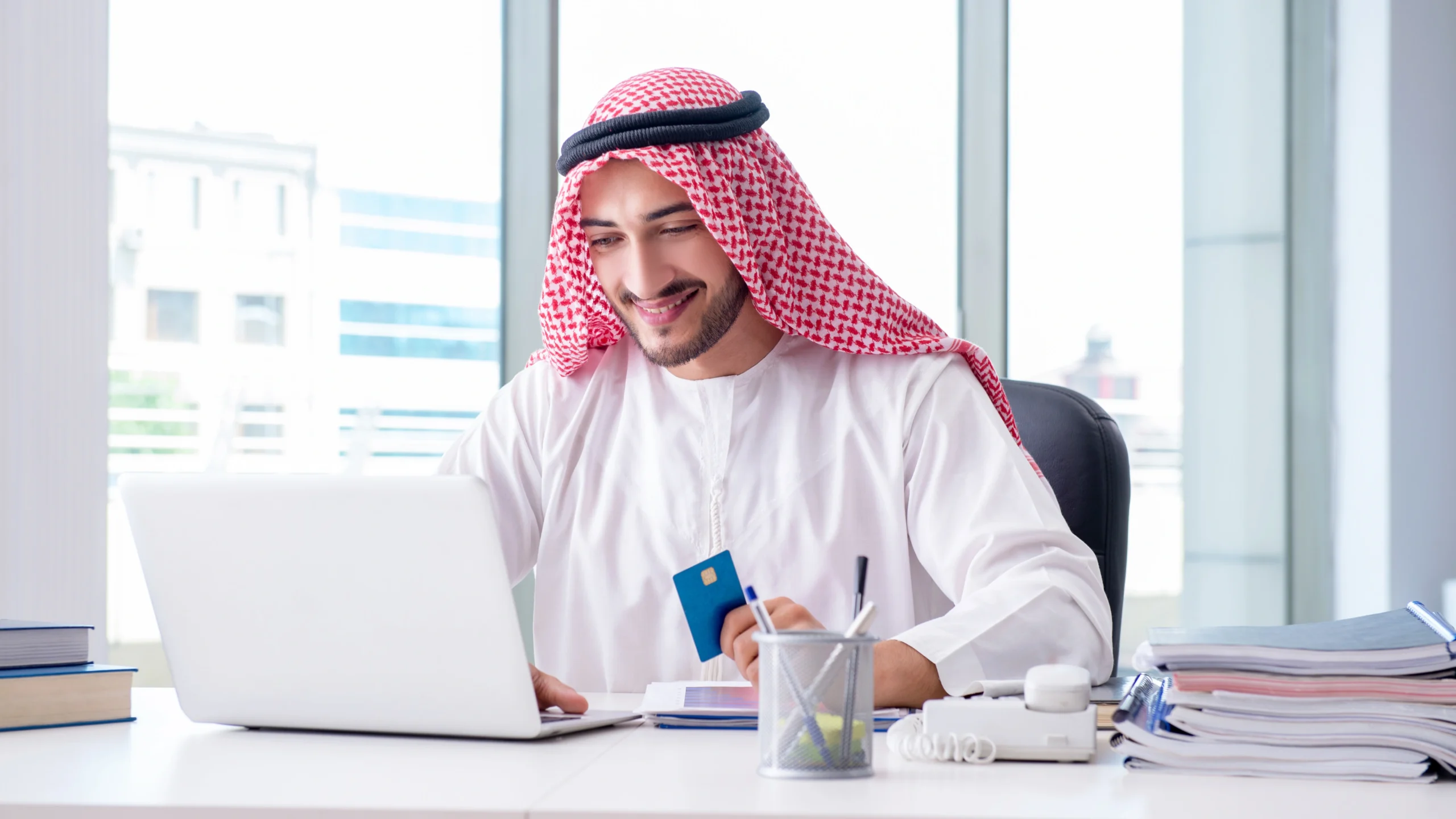 A man from the UAE sitting in his office using a laptop