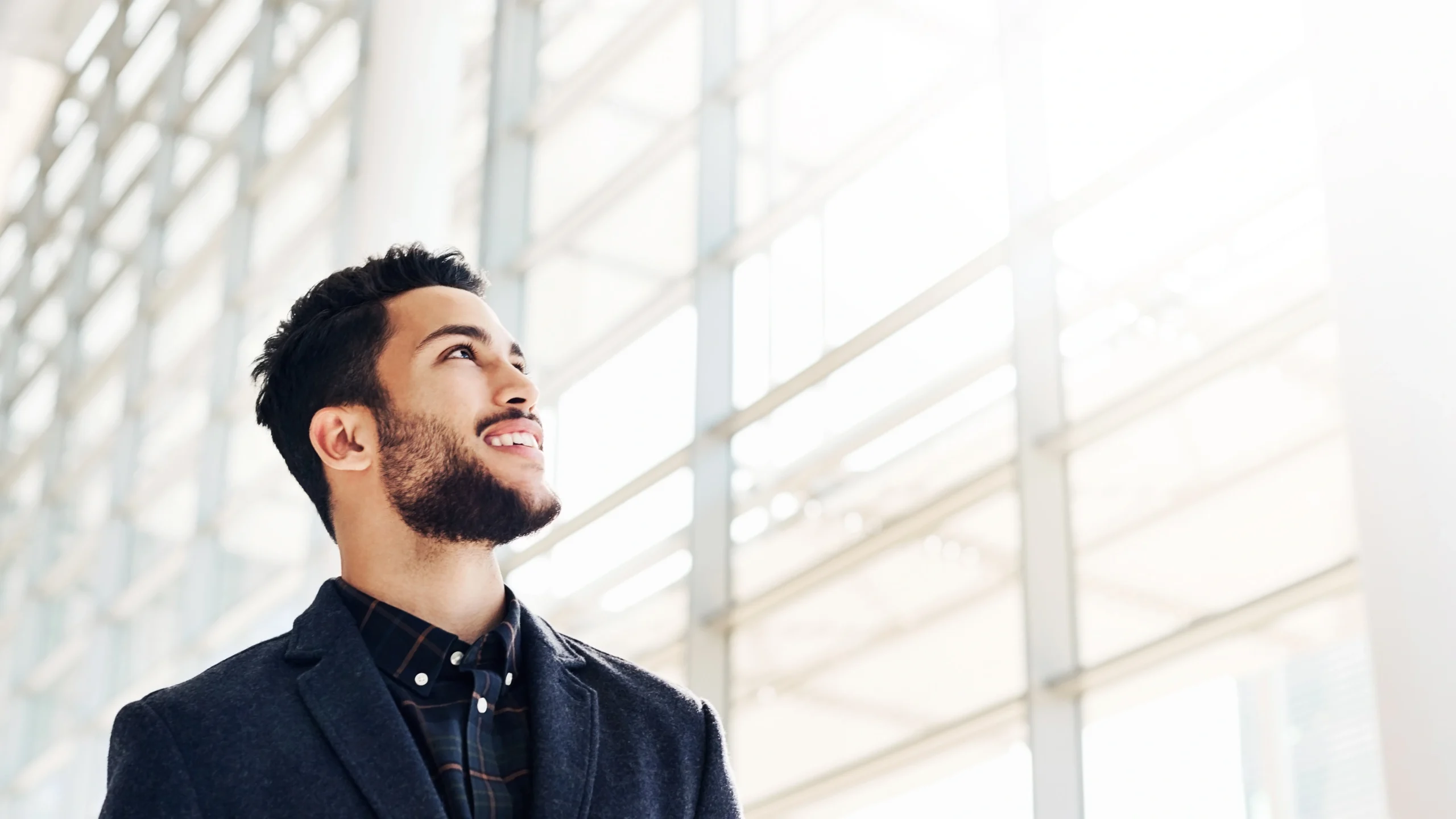 a businessman smiling and looking out the window of a large office building