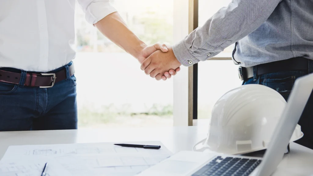 two men shaking hands with each other in an office after their meeting