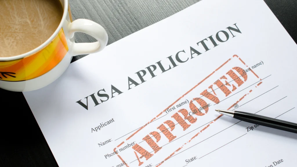 an approved visa application and a cup of tea on a table