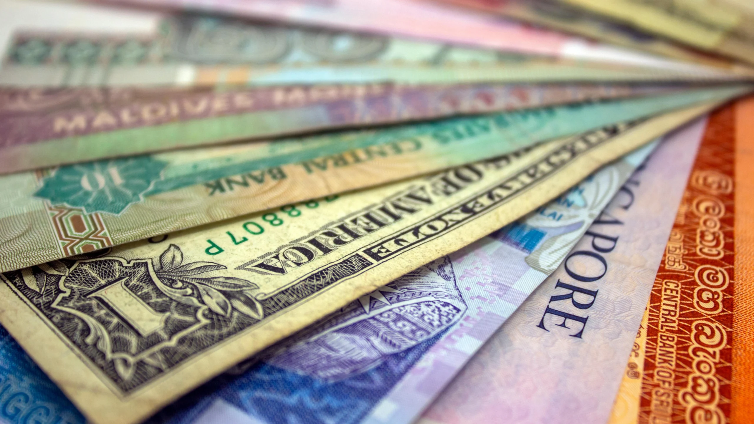 A dollar and many other currencies stacked together