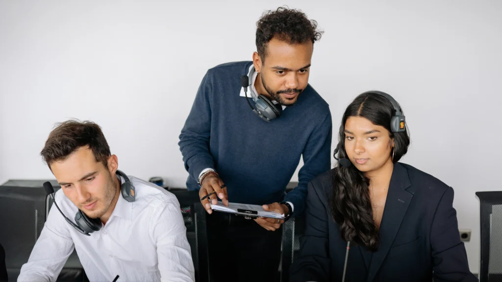 three people in an office looking at devices and doing work