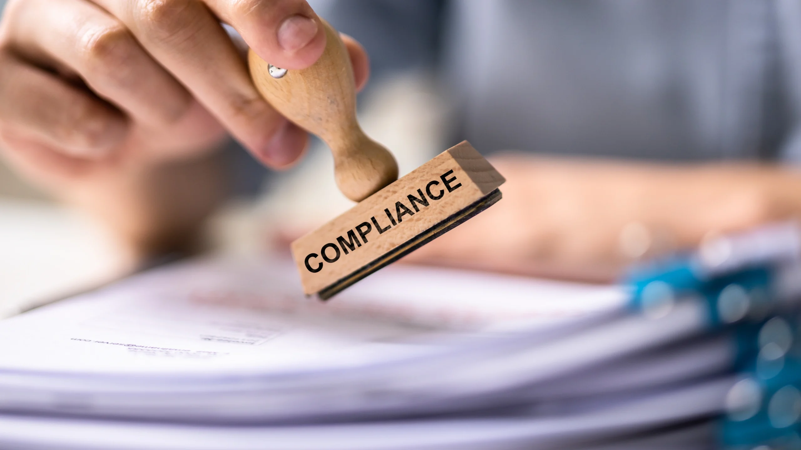 man about to use a stamp that says the word compliance