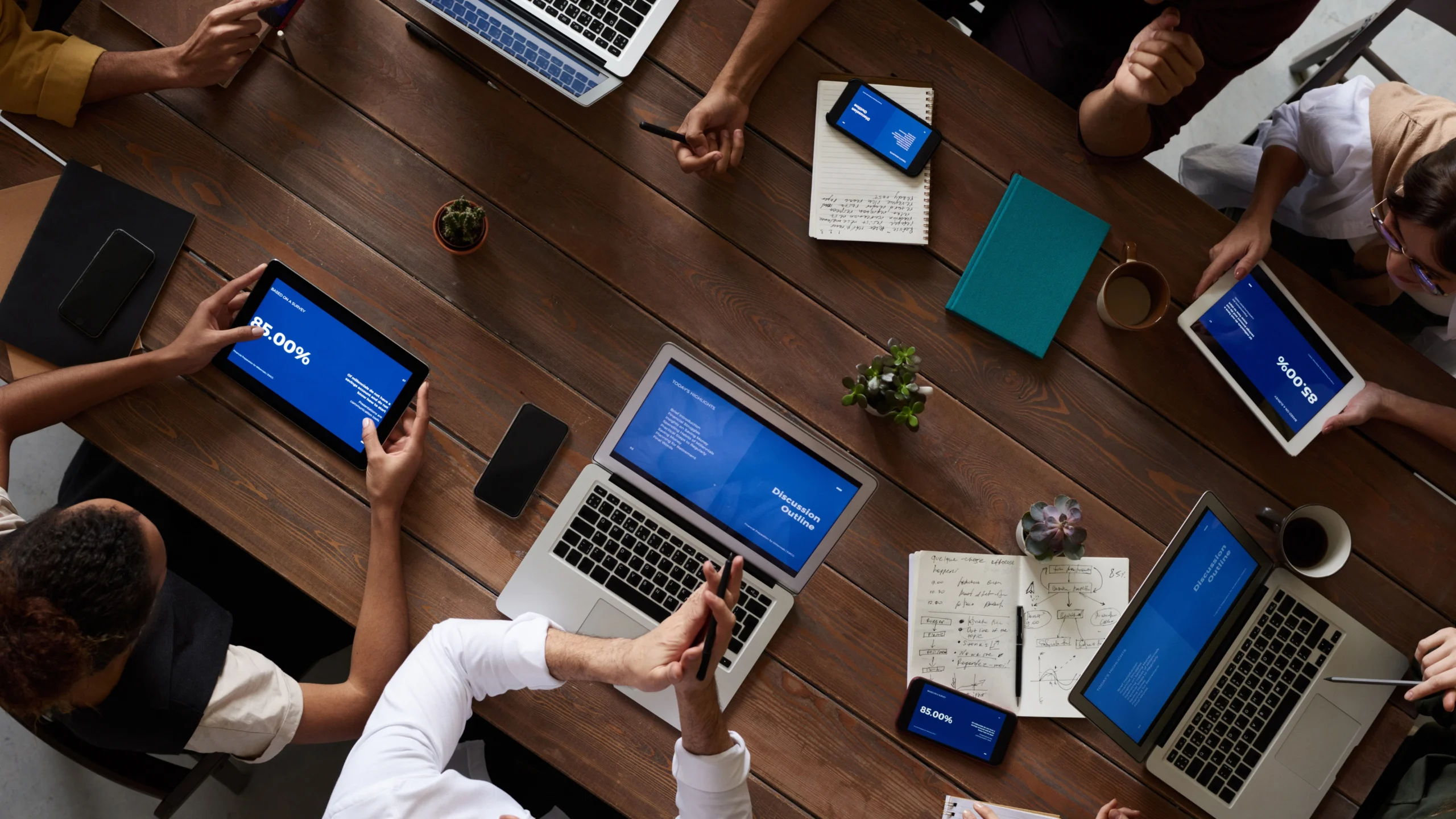 many people using various devices to do their jobs around the same table