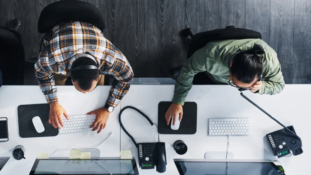 two men seen from above while sitting at their desk and working
