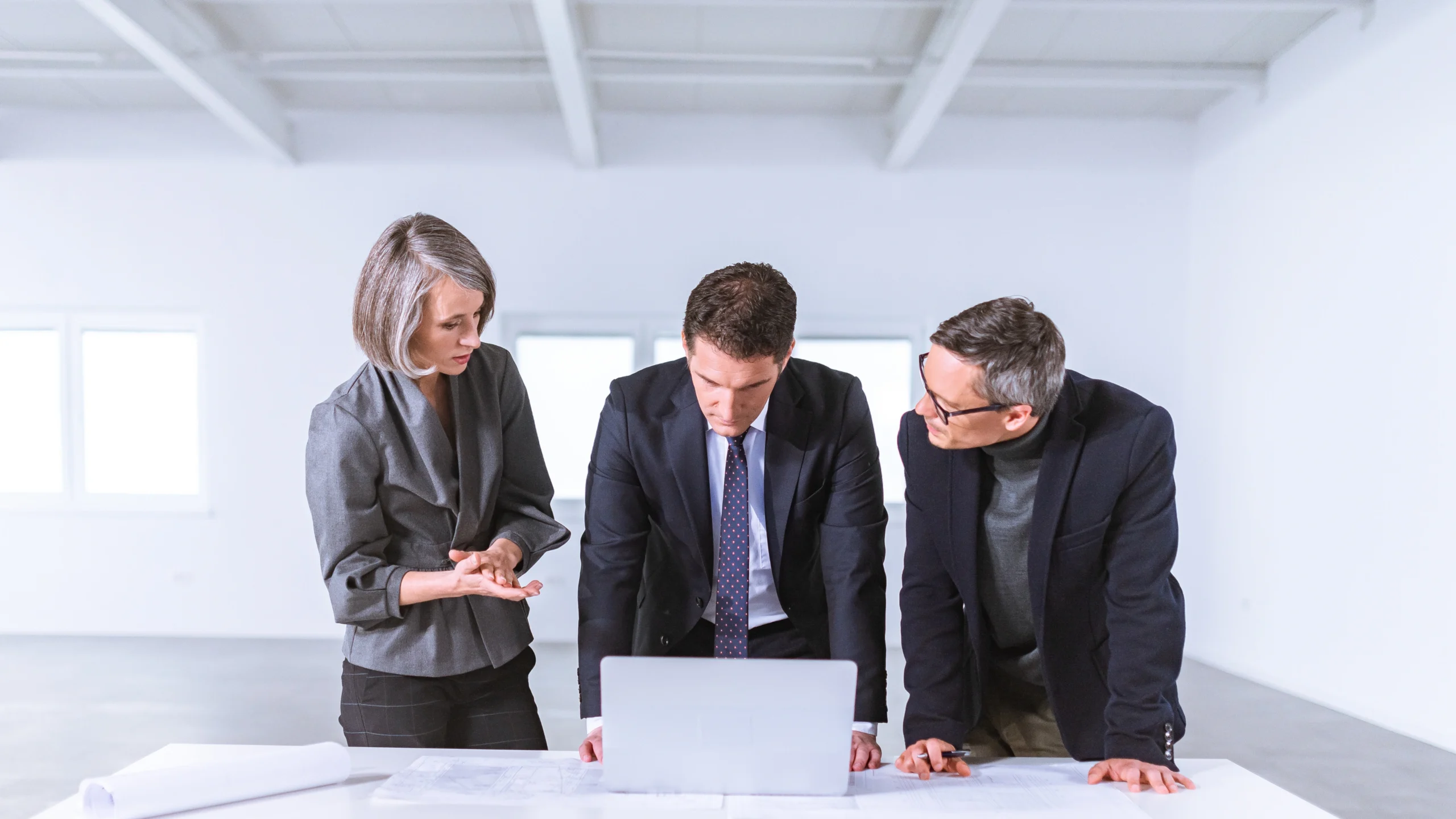 three people standing next to a desk and trying to make a decision