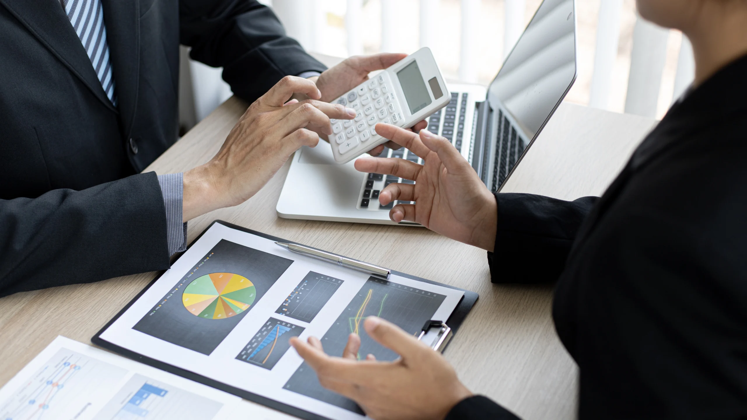 one person holding a calculator and going over numbers while another discusses work with him
