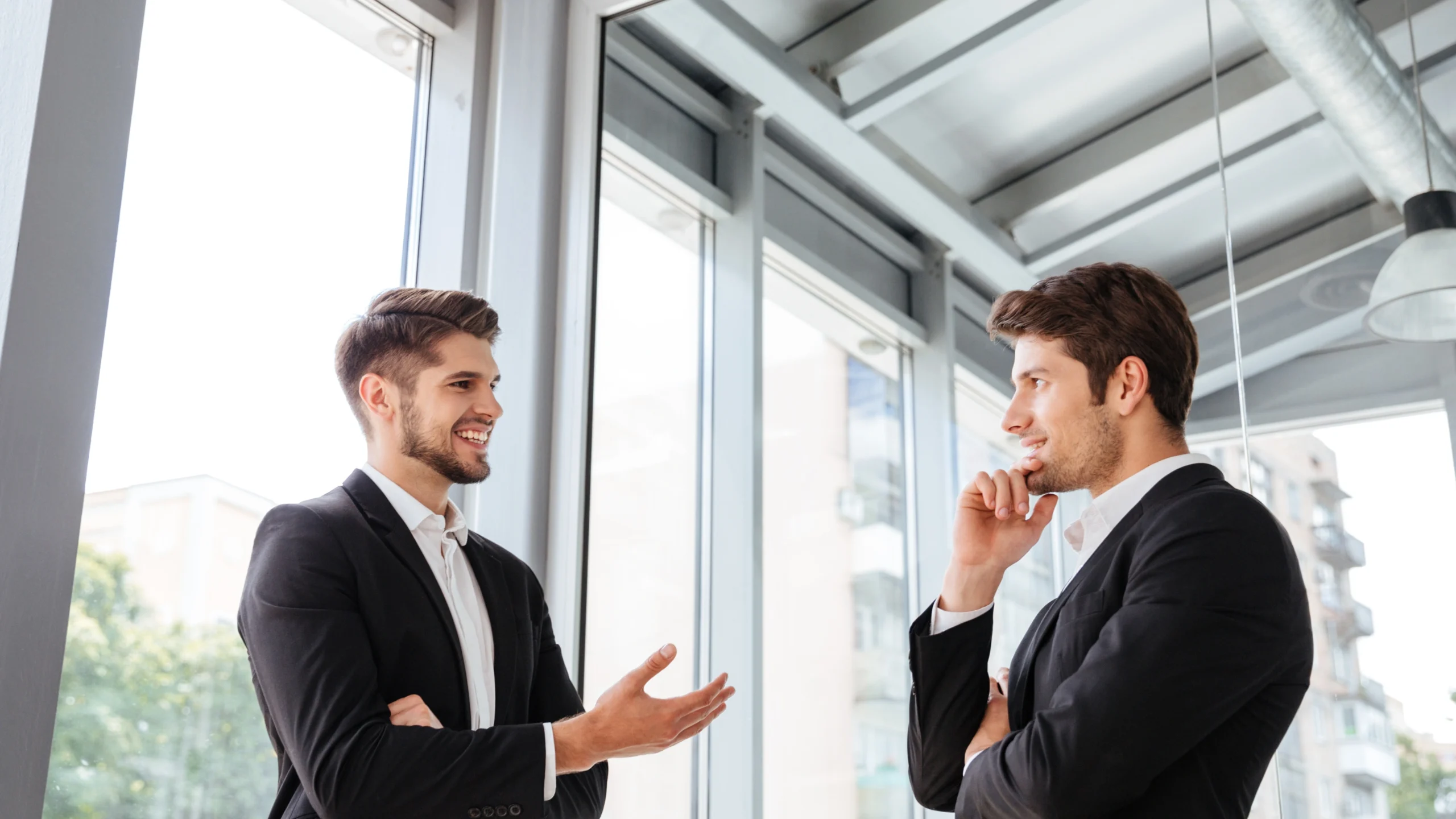 two businessmen discussing something in a hallway